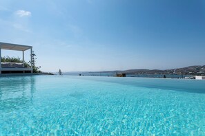 Una piscina cristallina con vista sul mare e sulle colline in lontananza.