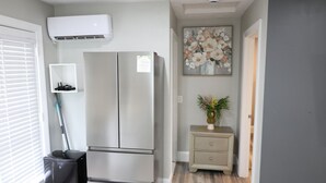 Una cocina compacta con un refrigerador de acero inoxidable, un mueble pequeño y un cuadro en la pared.