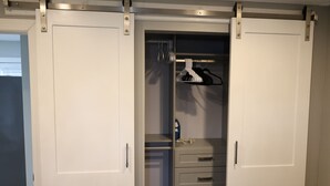 Un vestidor con puertas corredizas, una barra para colgar ropa y un conjunto de cajones.
