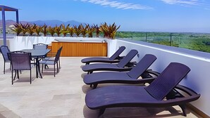 Eine Dachterrasse mit Liegestühlen, einem Tisch und Stühlen.