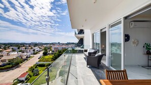 A balcony with a view of a residential area, a glass door, and a bench. - 2-Bedroom Flamingos • Heated Pool • Rooftop (Flamingos)