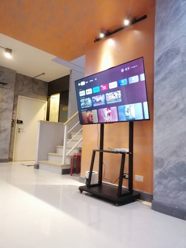 Un intérieur moderne avec un téléviseur à écran plat fixé sur un meuble, un escalier et une porte.
