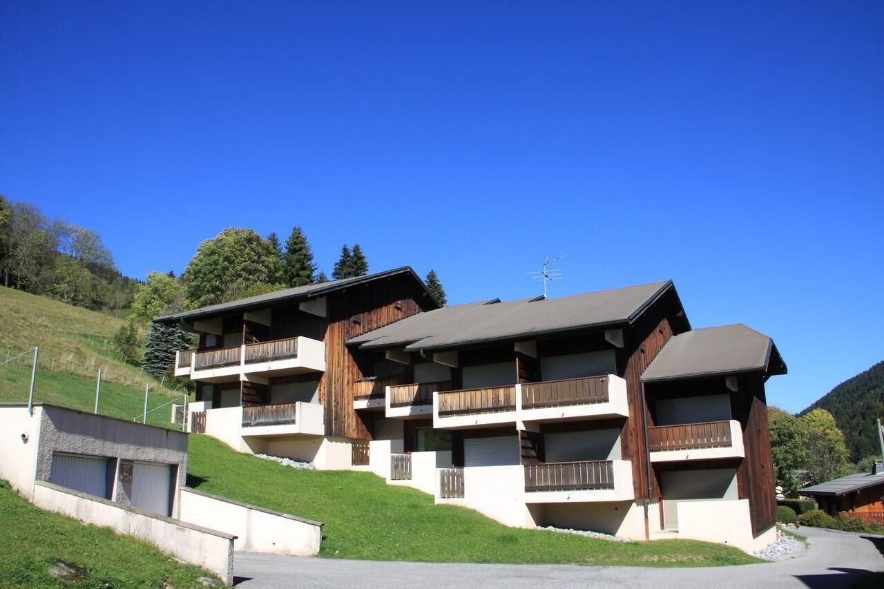 Un immeuble à plusieurs étages doté de balcons, situé sur une colline, avec un ciel bleu dégagé.