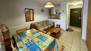 A compact living space with a sofa, a dining table, and a kitchen area.