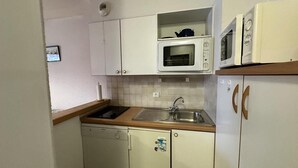 A compact kitchen with white cabinets, a microwave, a sink, and a dishwasher.