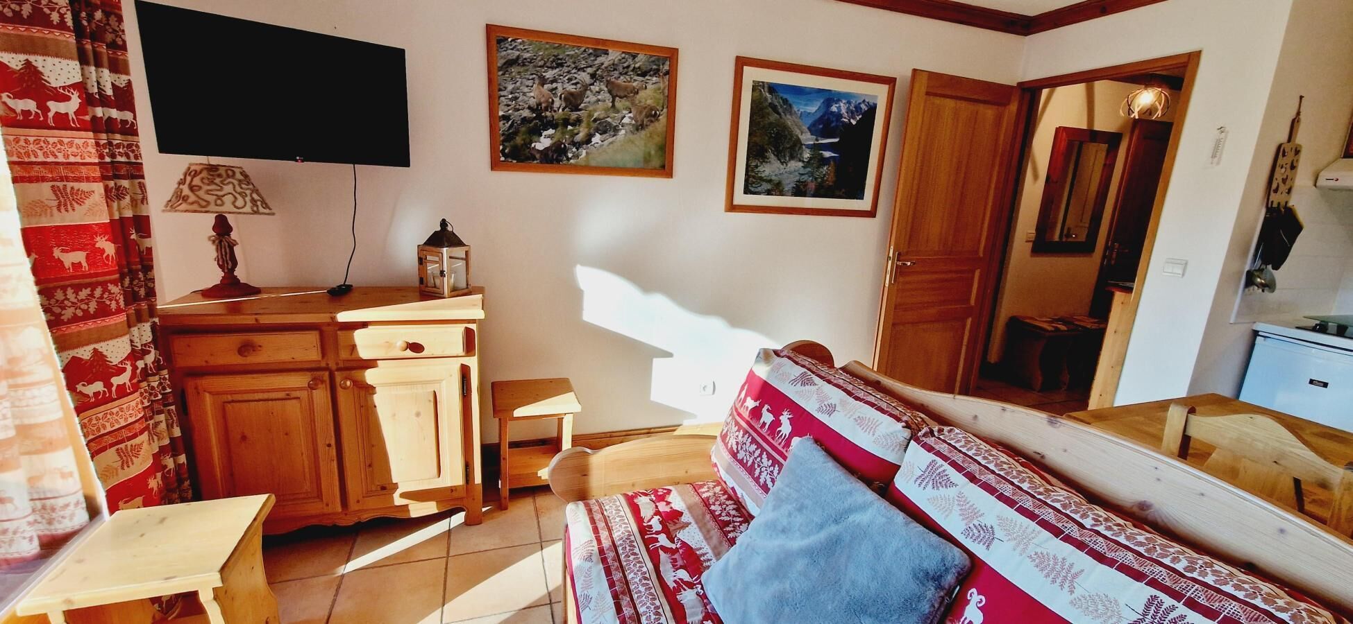 Uma sala de estar aconchegante com um sofá de madeira, uma mesinha, um armário e uma TV na parede.