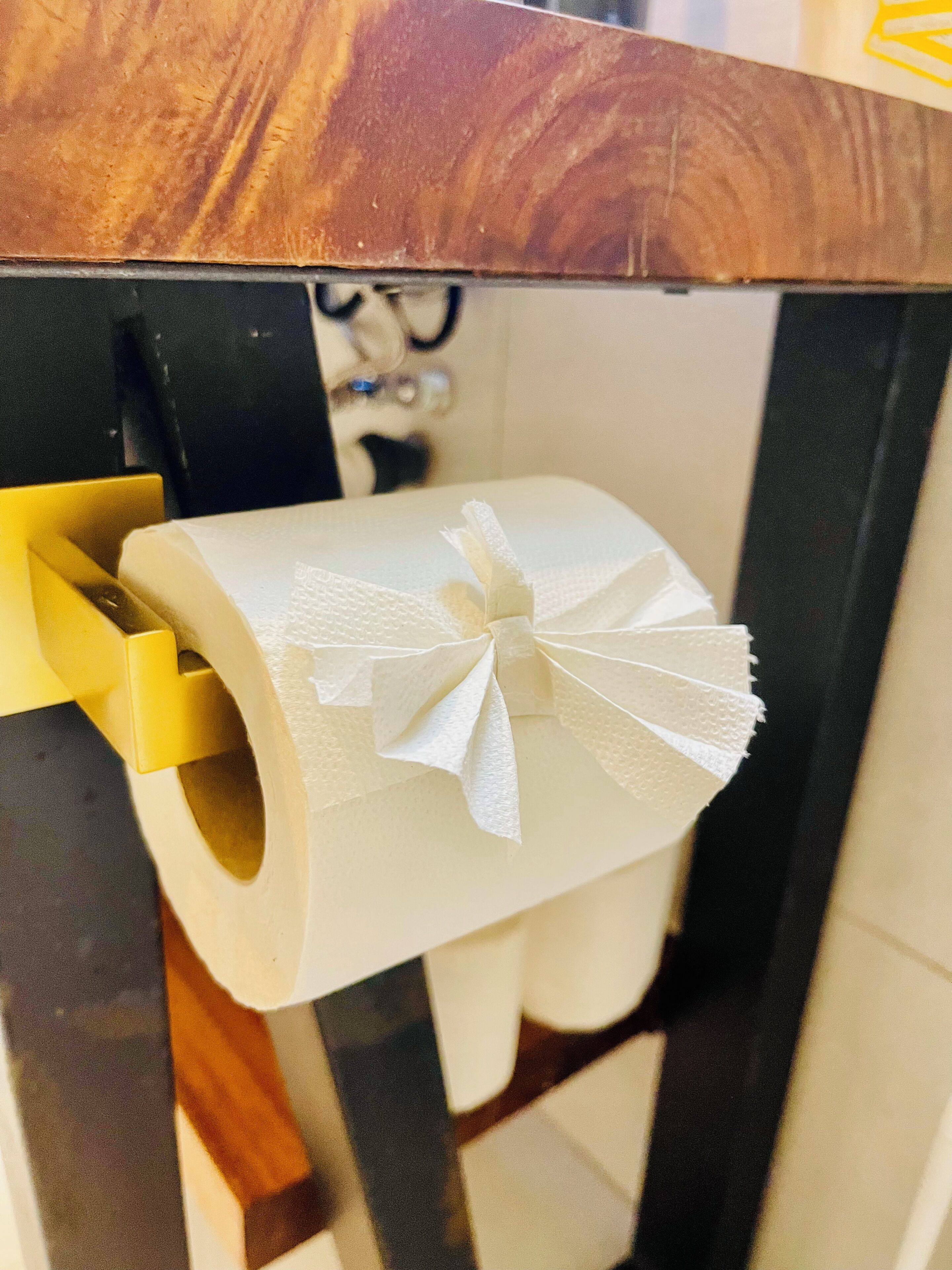 A toilet paper roll with a decorative bow on a toilet paper holder.