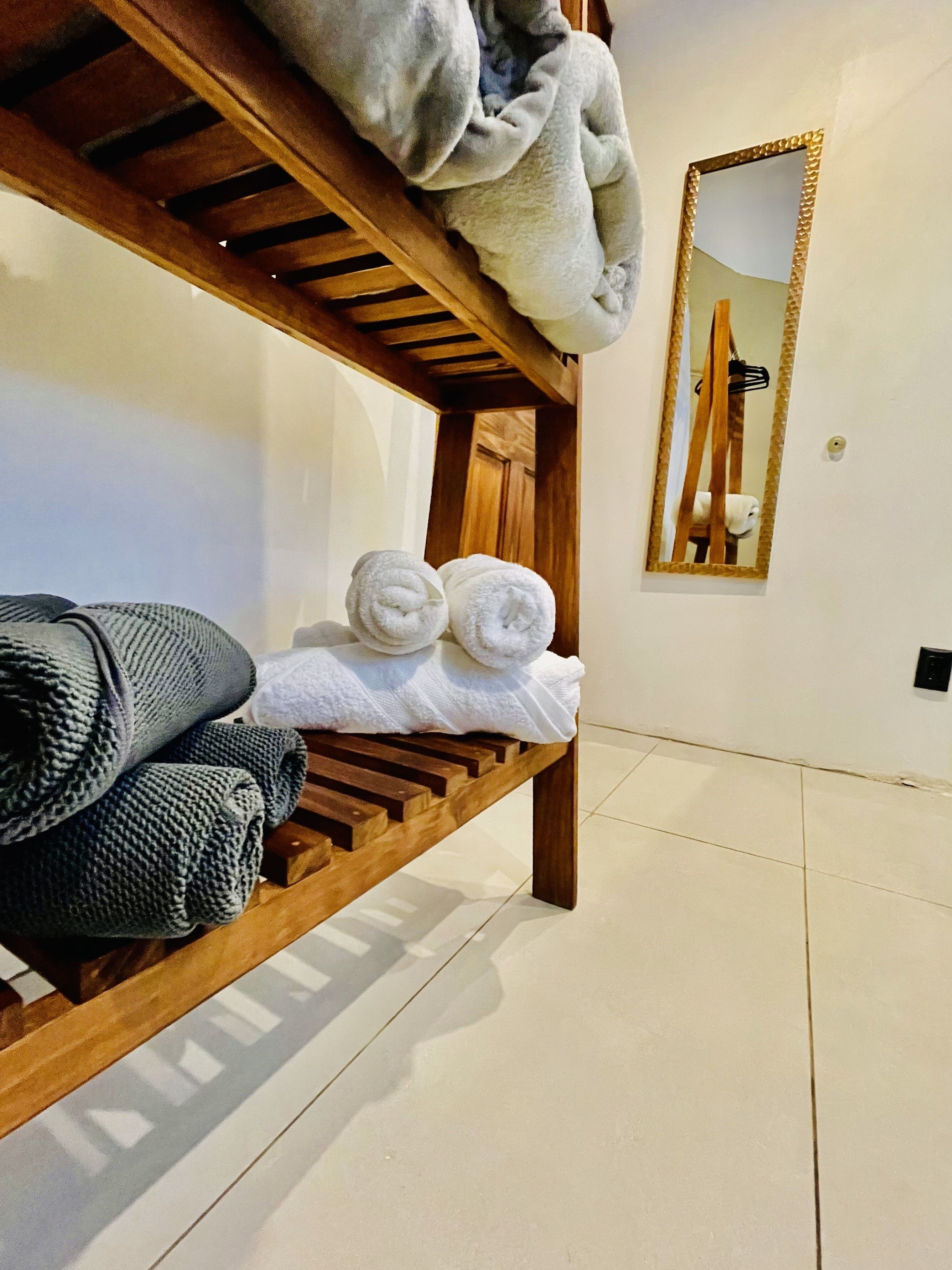 Una cama litera de madera con toallas y una manta tejida.