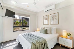 A hotel room with a bed, bedside tables, a TV, and a window with a view.
