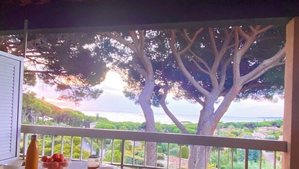Comedor con una mesa dispuesta para dos, con vista panorámica a árboles y una masa de agua.