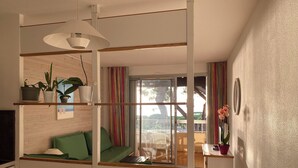 Una habitación moderna y luminosa con comedor, una kitchenette pequeña y un balcón con vistas al exterior.