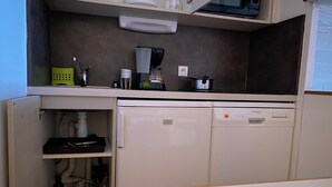 Cocina compacta equipada con lavavajillas, microondas y cafetera.