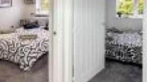 Una stanza con un letto grande, un letto più piccolo e una porta che dà su un'altra stanza.