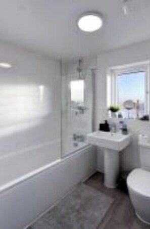 Een moderne badkamer met een bad, een wastafel en een toilet.