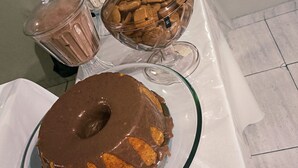 A dessert table with a chocolate-covered cake, a glass pitcher, and a bowl of cookies. - Solar Centro (Rio de Janeiro)
