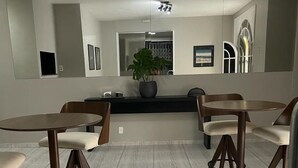 A modern kitchen with white cabinets, a central island, and bar stools. - Solar Centro (Rio de Janeiro)