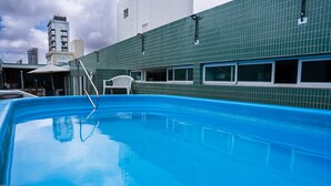 A swimming pool with a view of a building with green tiled walls and windows. - Magnific (João Pessoa)