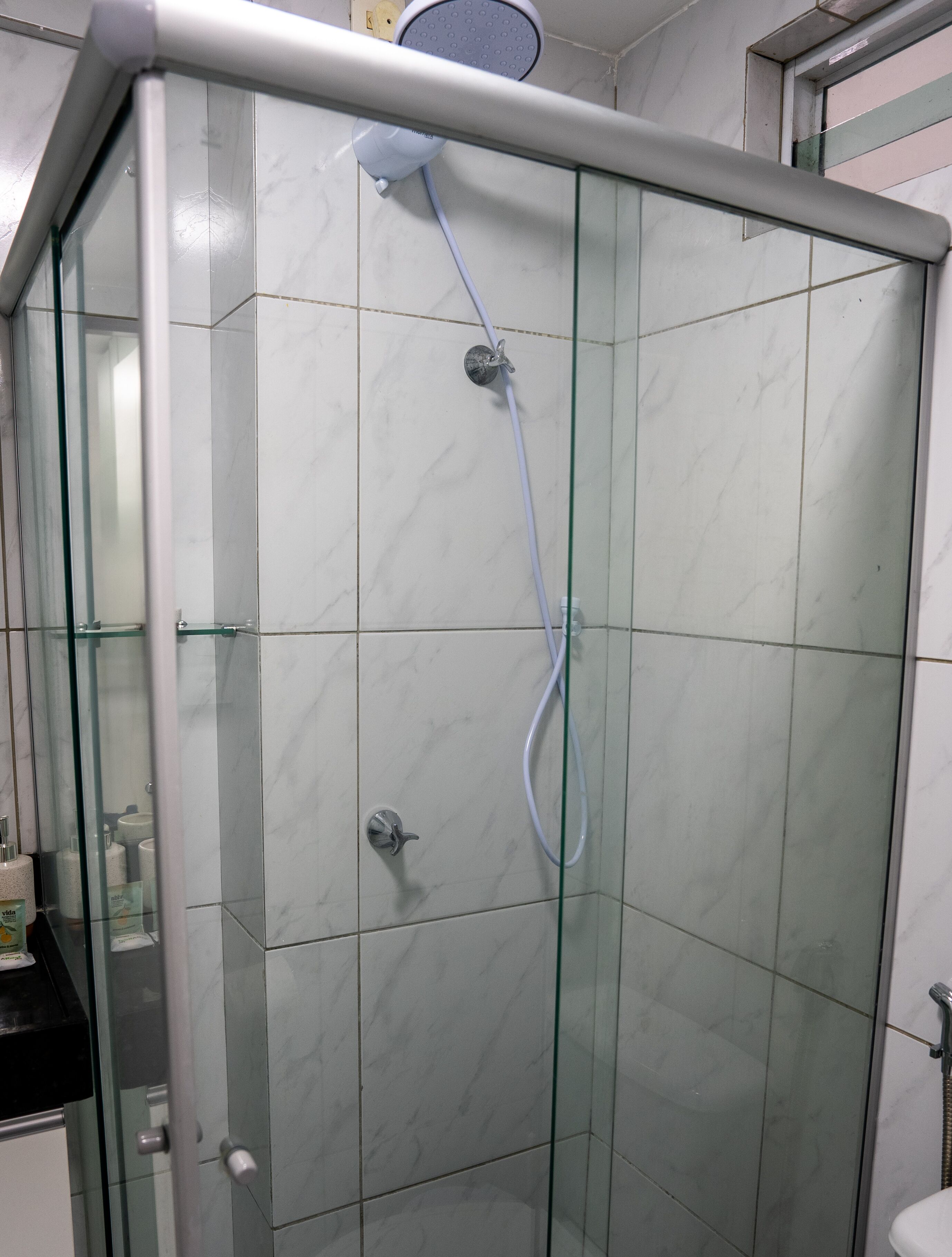 Ducha envidriada amb plat de ducha suau i aixeta de pared.