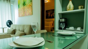 A dining area with a glass table, two plates, a wine glass, and a coffee maker. - Magnific (João Pessoa)