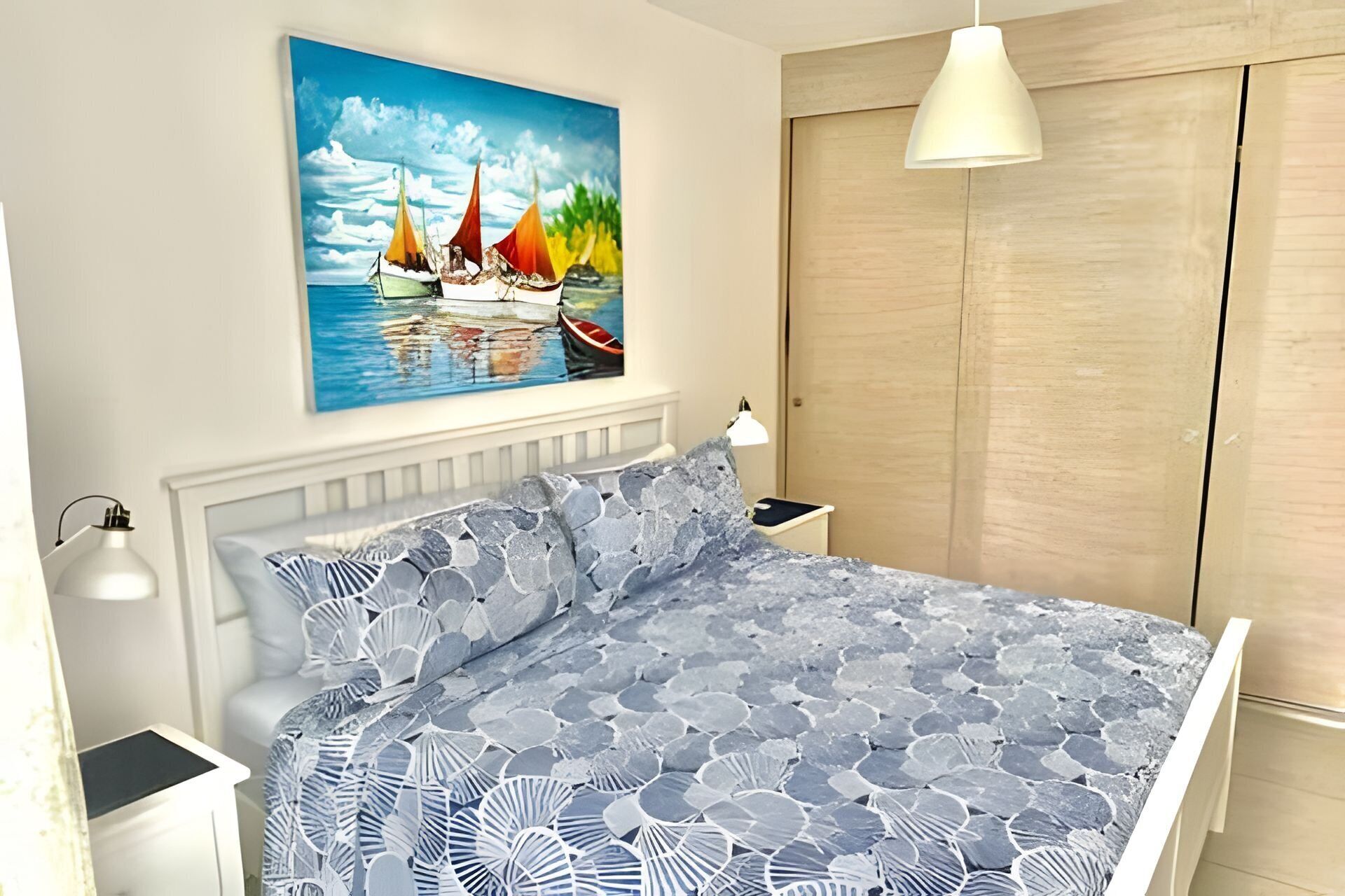 Ein Schlafzimmer mit Bett, einem Bild von Booten auf dem Wasser, einem Kleiderschrank und einer Nachttischlampe.