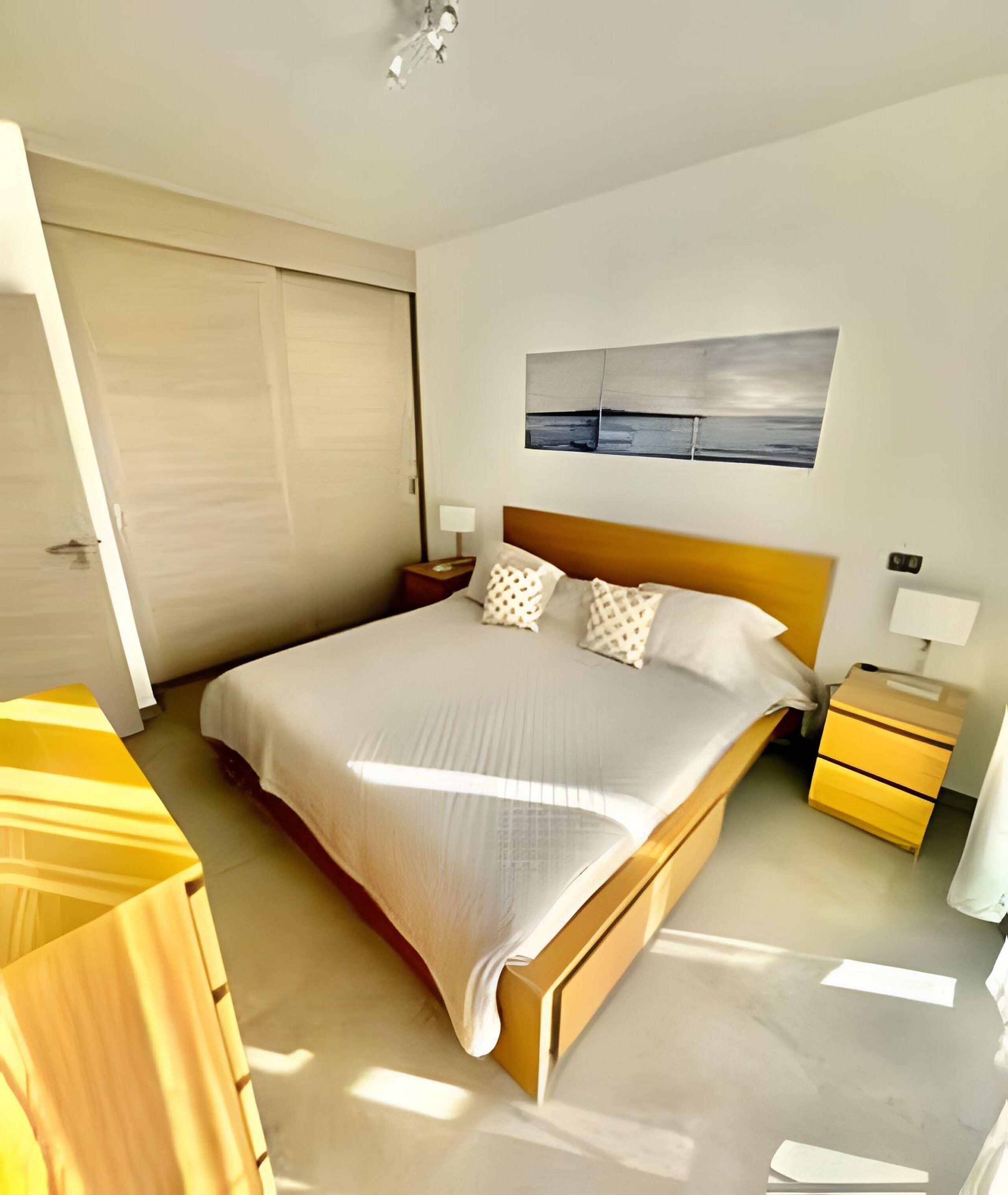 Un dormitorio moderno con una cama grande, cabecera de madera y un cuadro en la pared.