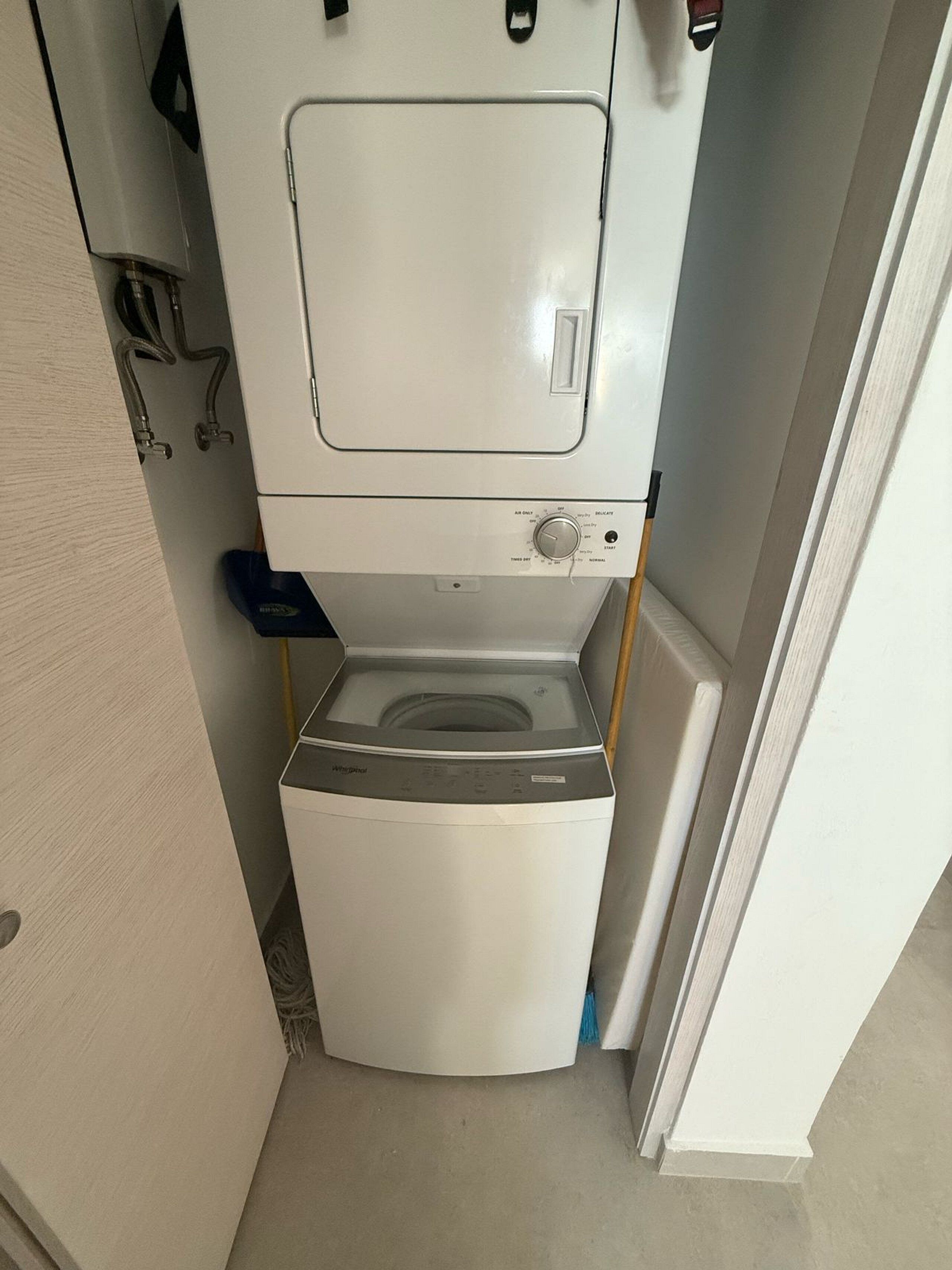 A compact, white, two-basin washer and dryer unit in a small bathroom.