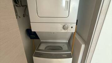 Eine kompakte, weiße Waschmaschine und Trockner-Kombination mit zwei Waschbecken in einem kleinen Badezimmer.