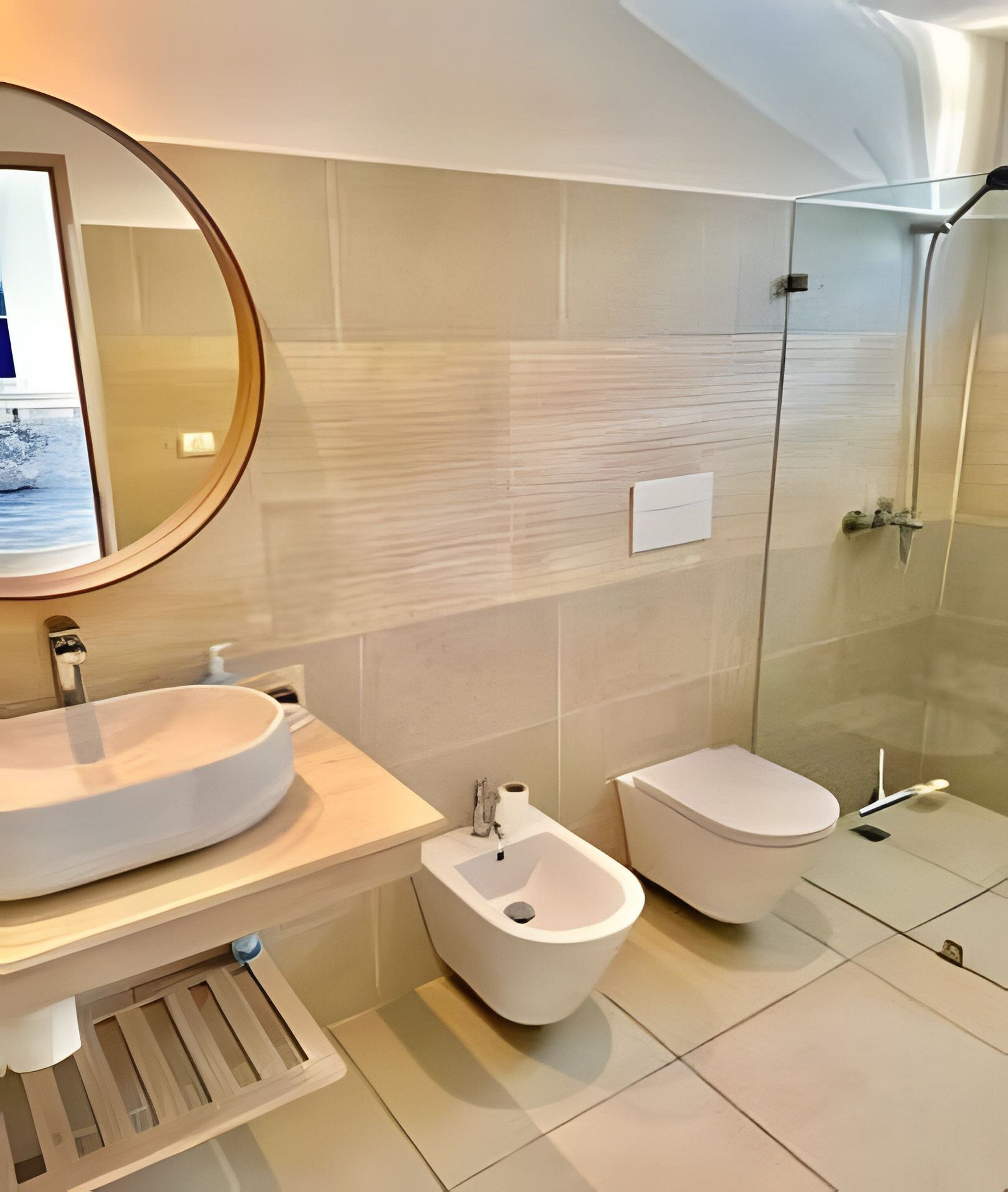 Une salle de bain moderne avec un lavabo rond, un bidet et des toilettes.