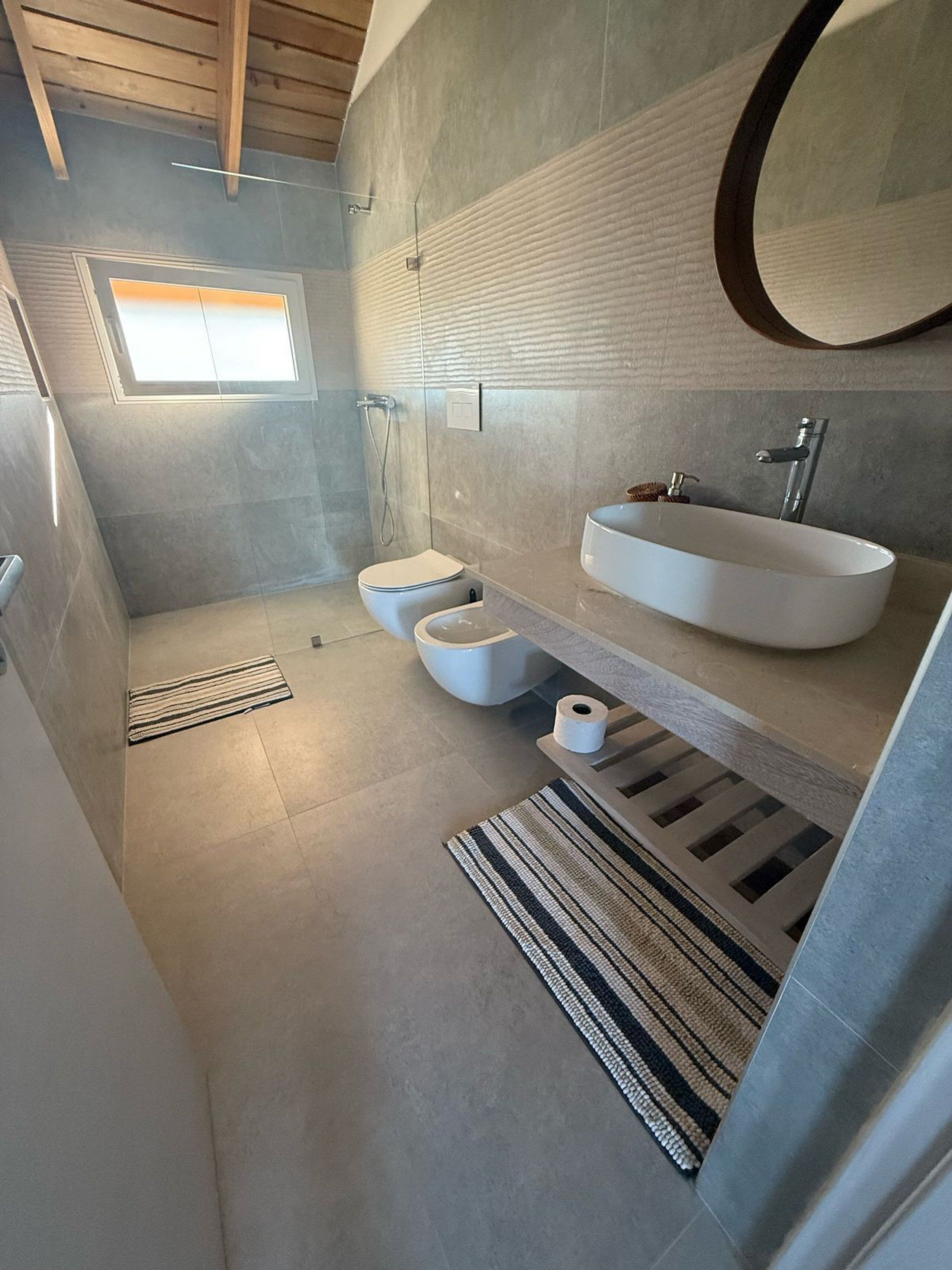 Ein modernes Badezimmer mit barrierefreier Dusche, Toilette und Waschbecken.