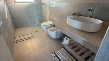 Ein modernes Badezimmer mit barrierefreier Dusche, Toilette und Waschbecken.
