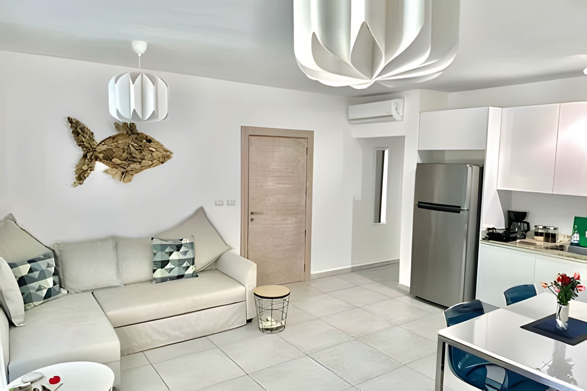 Een moderne woonkamer met een bank, een kleine ronde tafel en een eethoek met tafel en stoelen.