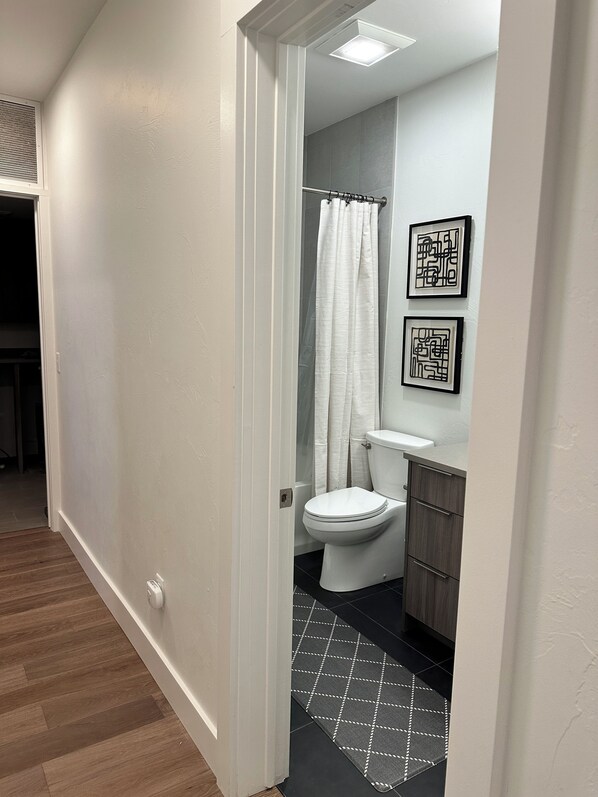 A bathroom with a toilet, shower curtain, and two framed pictures on the wall.
