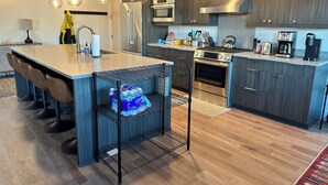 Una cocina moderna con una isla central, electrodomésticos de acero inoxidable y una cafetera.