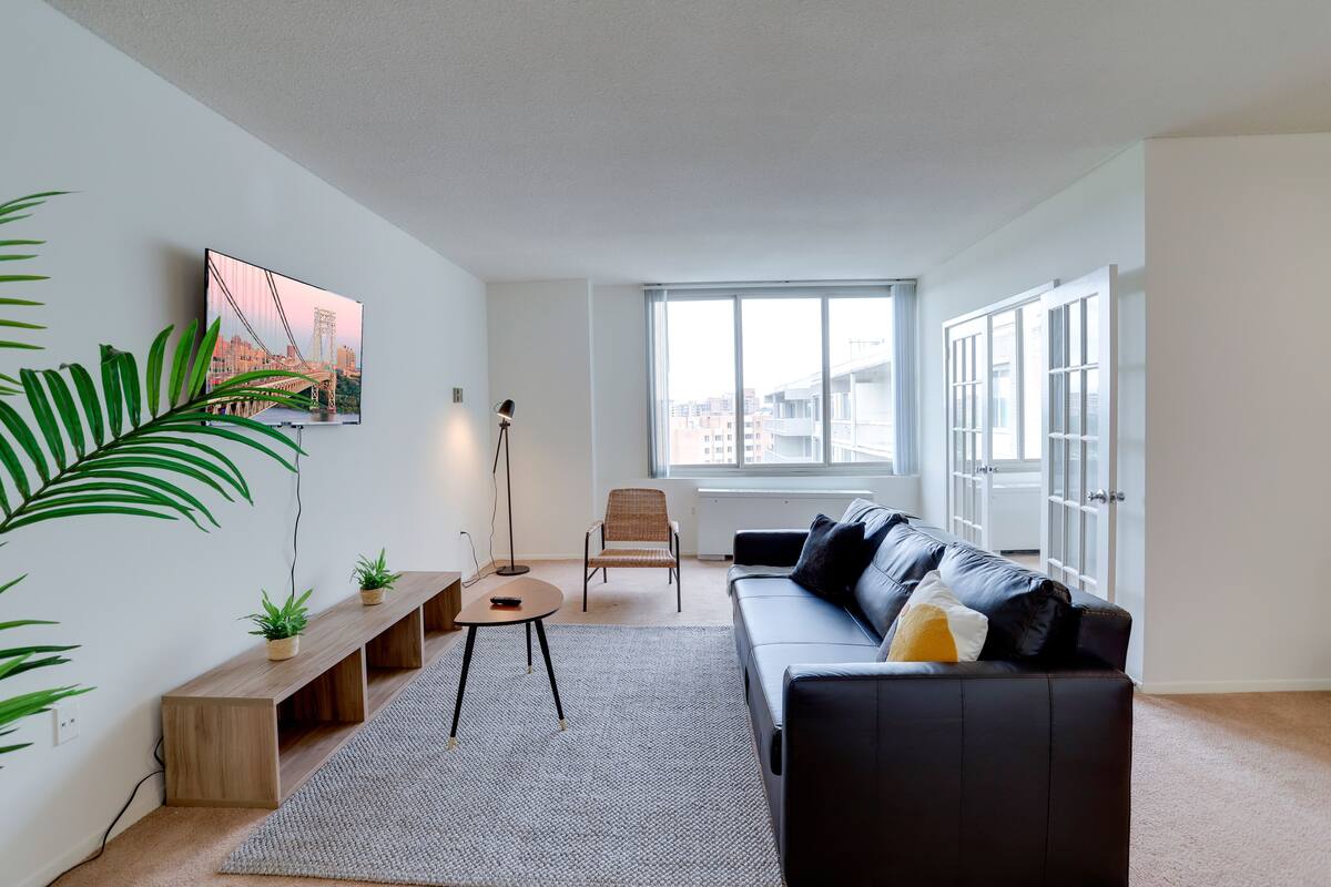 A modern living room with a sofa, a chair, a coffee table, and a TV mounted on the wall.