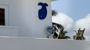 A building with a white exterior, a blue logo, and a satellite dish. - Joy Beach Lodge (Sekondi-Takoradi)