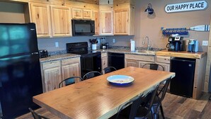 Une cuisine moderne avec des meubles en bois, un réfrigérateur noir, un four à micro-ondes, une cuisinière et une machine à café.