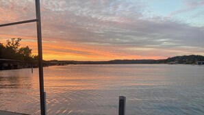 Une vue sur le bord de l’eau, avec un coucher de soleil, une eau calme et un quai.