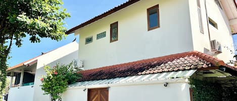 A two-story building with a tiled roof, a wooden door, and small windows.