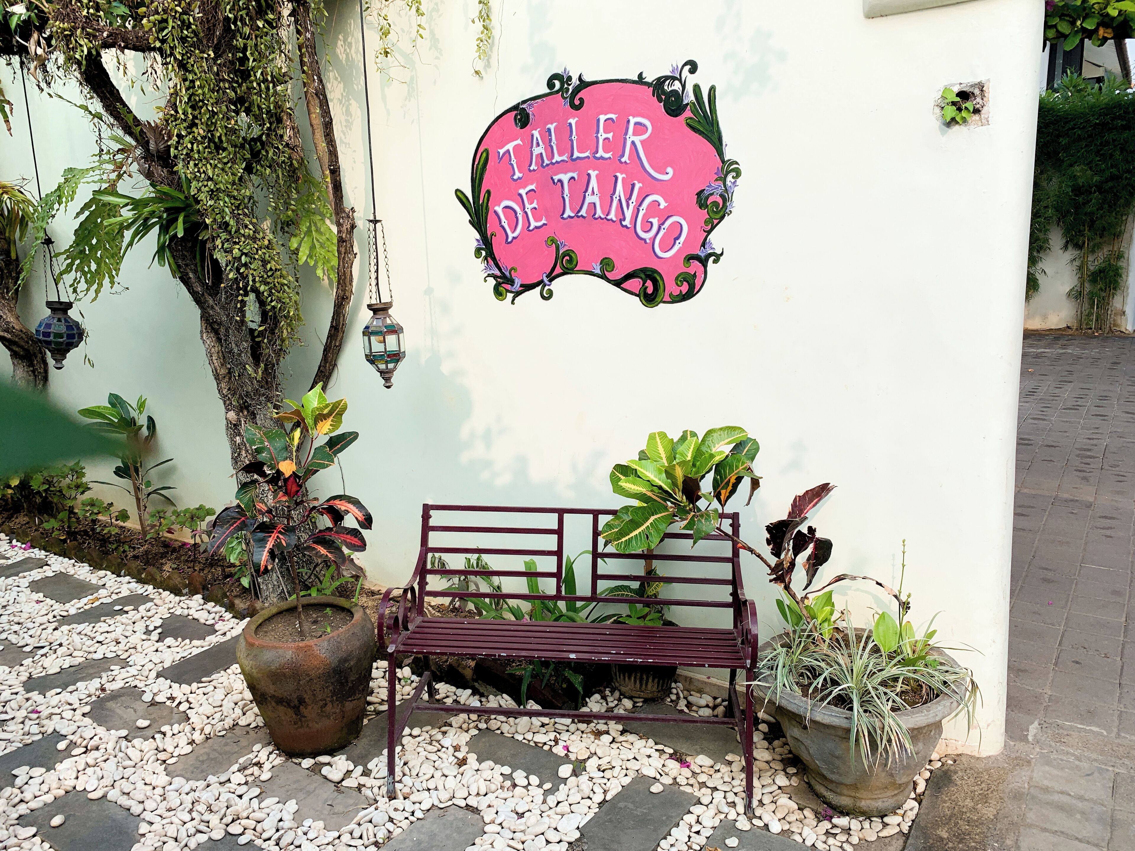A bench with a sign reading "Taller de Tango" against a wall.