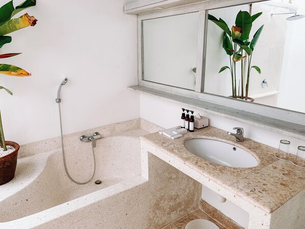 Un baño con una bañera independiente, un lavabo y un espejo sobre él.