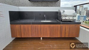 Eine moderne Außenküche mit integriertem Spülbecken und Grill, Holdekor-Schränken und einer gefliesten Rückwand.