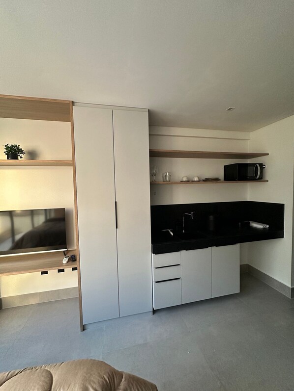 A modern kitchen with built-in appliances, a flat-screen TV, and a minimalist design. - Get By Side (João Pessoa)