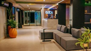 Eine moderne Lobby mit Empfangstresen, Sitzgelegenheiten und Topfpflanzen.