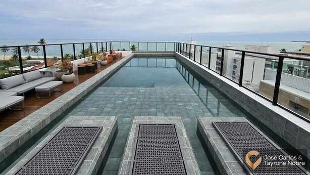 Ein Dachpool mit Infinity-Kante, umgeben von Sitzmöglichkeiten und Blick auf den Ozean.