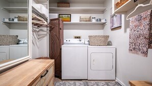 A compact laundry room with a washing machine, dryer, and a wooden bench. - The Erin, 1 BR King Duplex by Velvet Ditch Villas (Oxford)