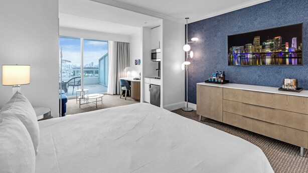 Habitación de hotel con una cama grande, un escritorio con computadora, televisión y vista a la ciudad.
