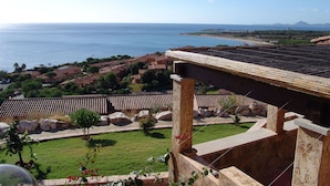 Vista costera con cielo despejado, una playa y una zona residencial con tejados de teja.