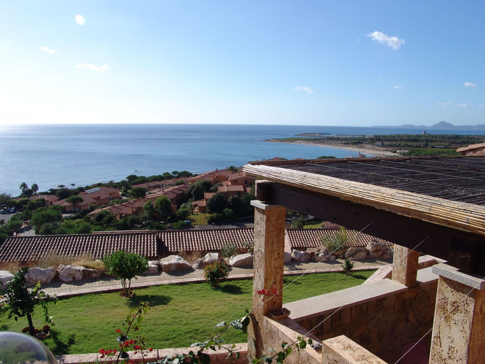 Vista costera con cielo despejado, una playa y una zona residencial con tejados de teja.