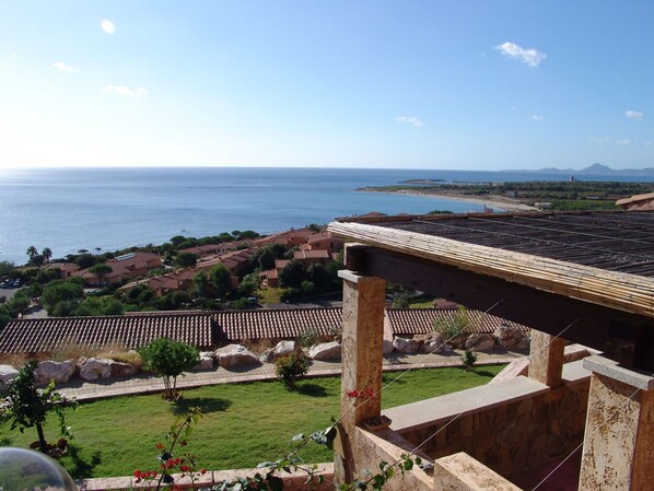 A coastal view with a clear sky, a beach, and a residential area with terracotta roofs.