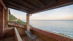 A balcony with a view of the sea, a chair, and a stone wall. - Villetta Seaside Sardegna (Villaputzu)